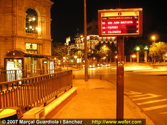 Panell informatiu al costat d'una parad de bus, anunciant el temps d'espera pel pròxim bus.